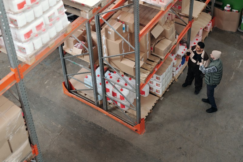 overhead and wide view shot of an Amazon warehouse full of packages and two people conversing
